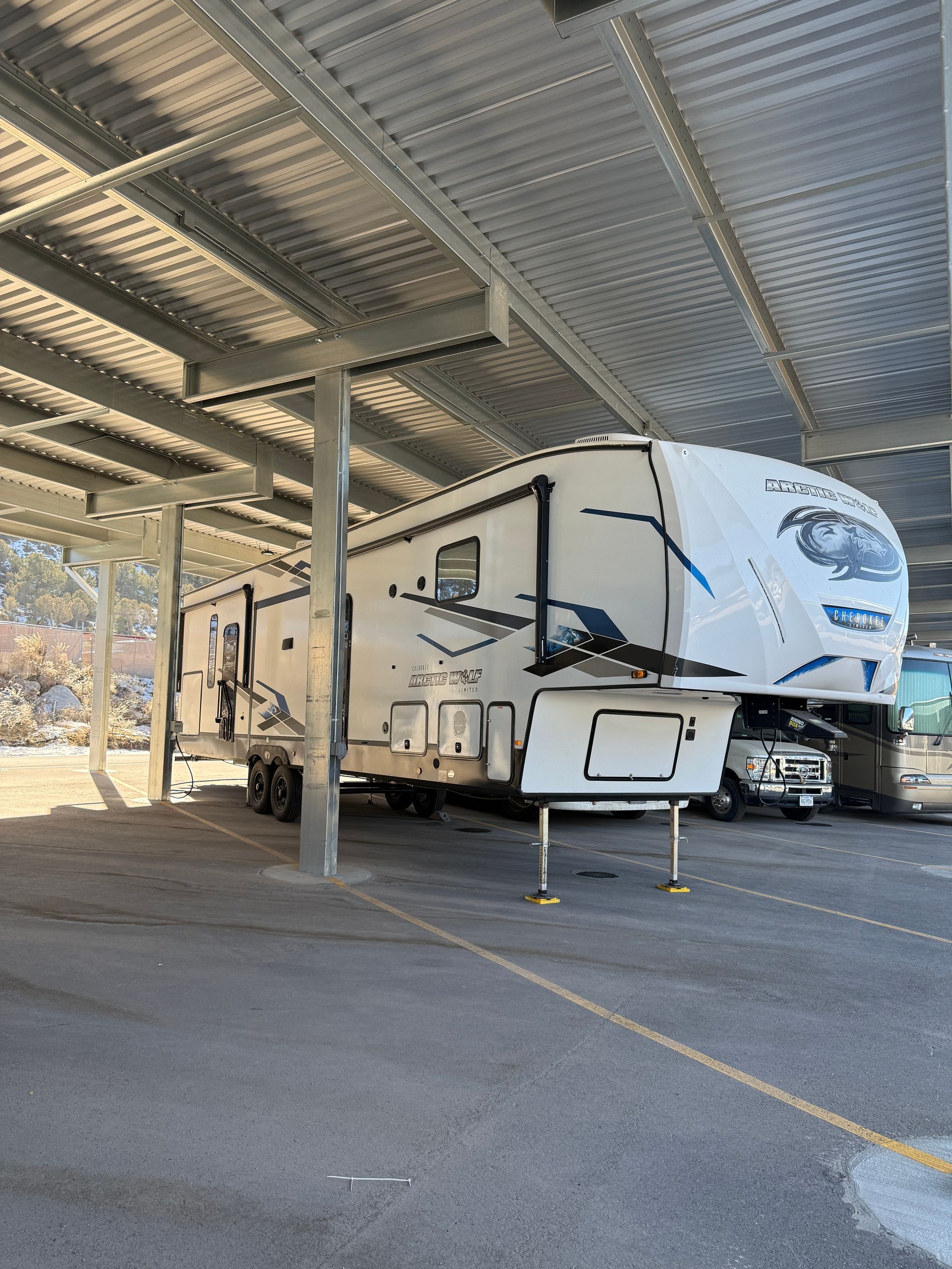 Fifth-wheel trailer parked under covered RV storage with power access