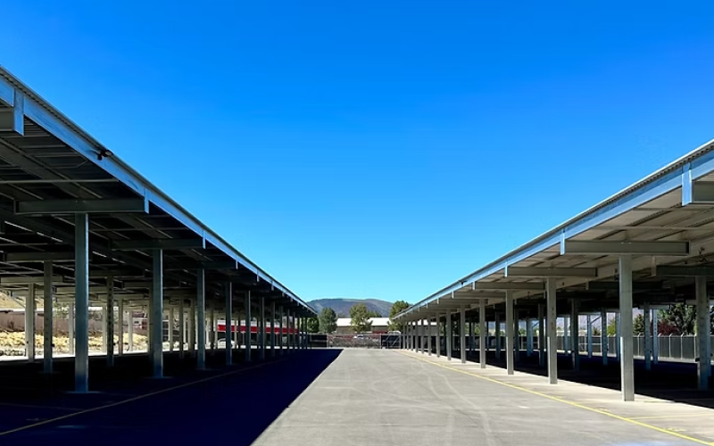 Wide view of covered RV storage lanes with steel canopies and asphalt surface

