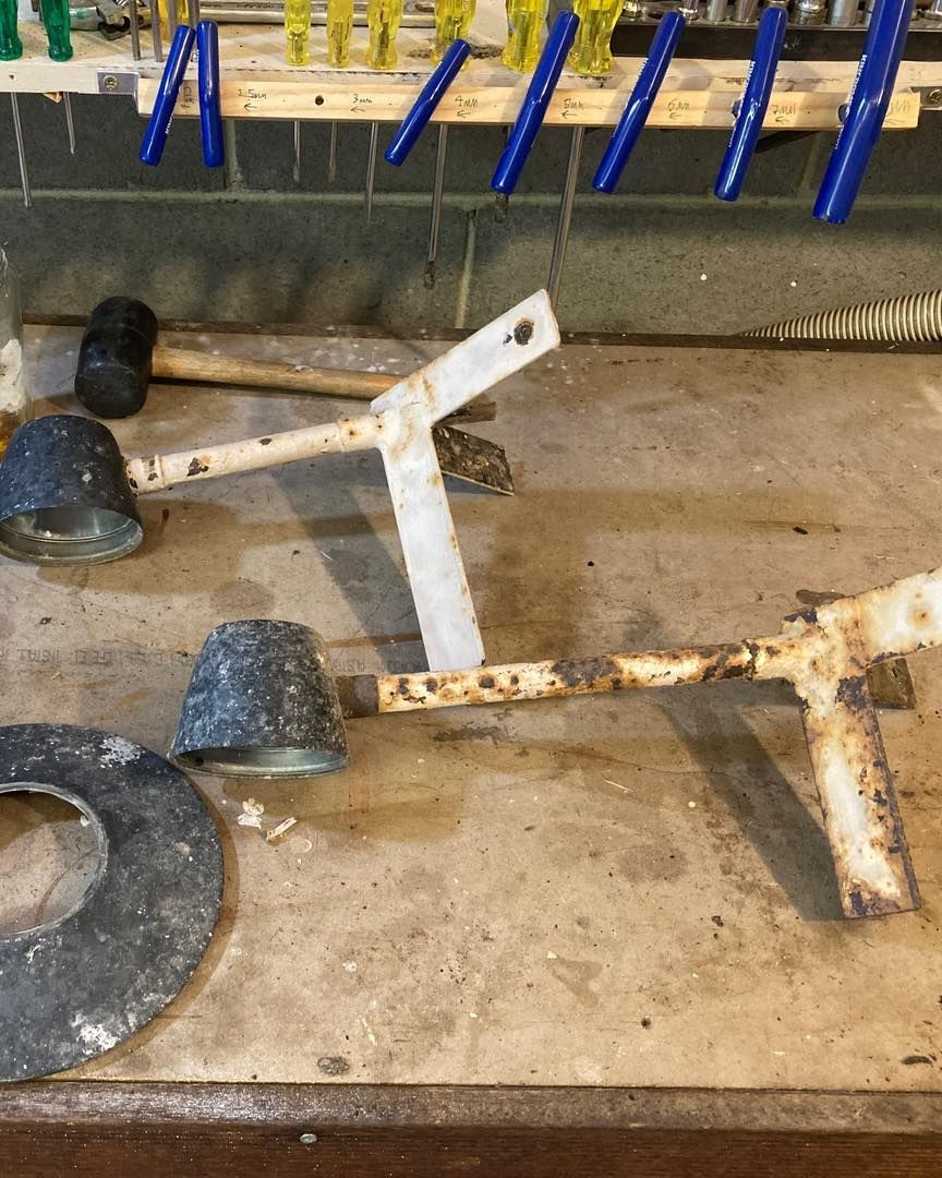 Workbench with tools: hammer, clamps, rusted metal bracket and cone-shaped items.