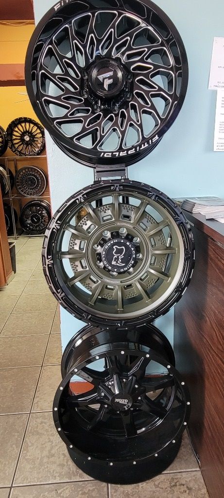 A stack of black and dirty white wheels sitting on top of each other on a wall.