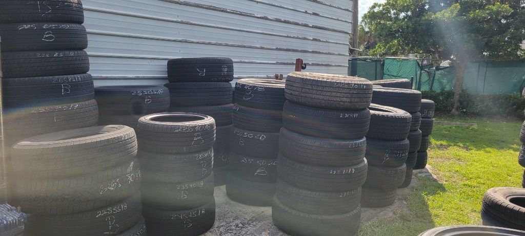 A bunch of tires are stacked on top of each other in a yard.