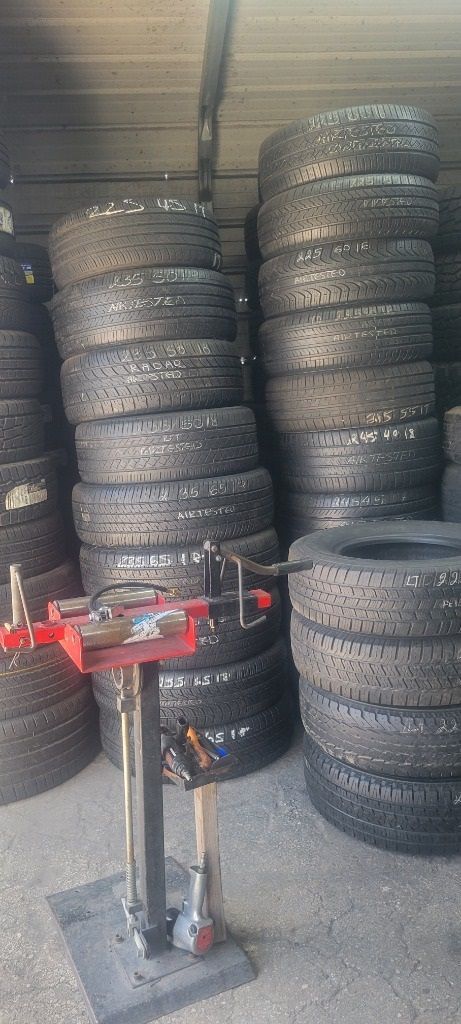 A bunch of used tires are stacked on top of each other in a garage.