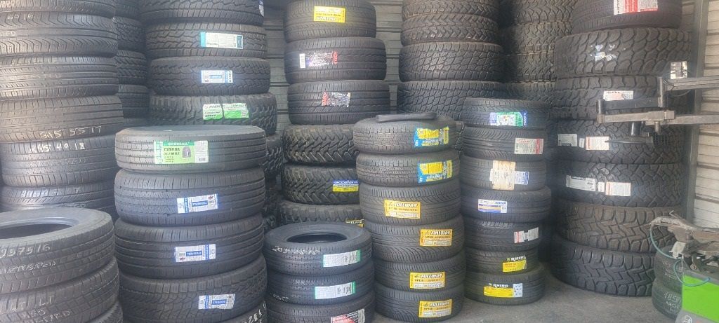 A bunch of quality used tires are stacked on top of each other in a garage.