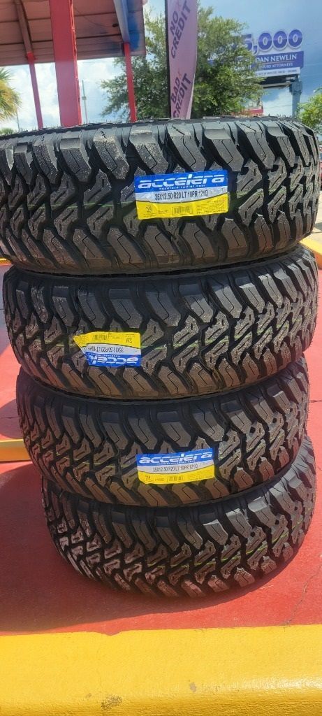 Three new tires are stacked on top of each other on a yellow surface.