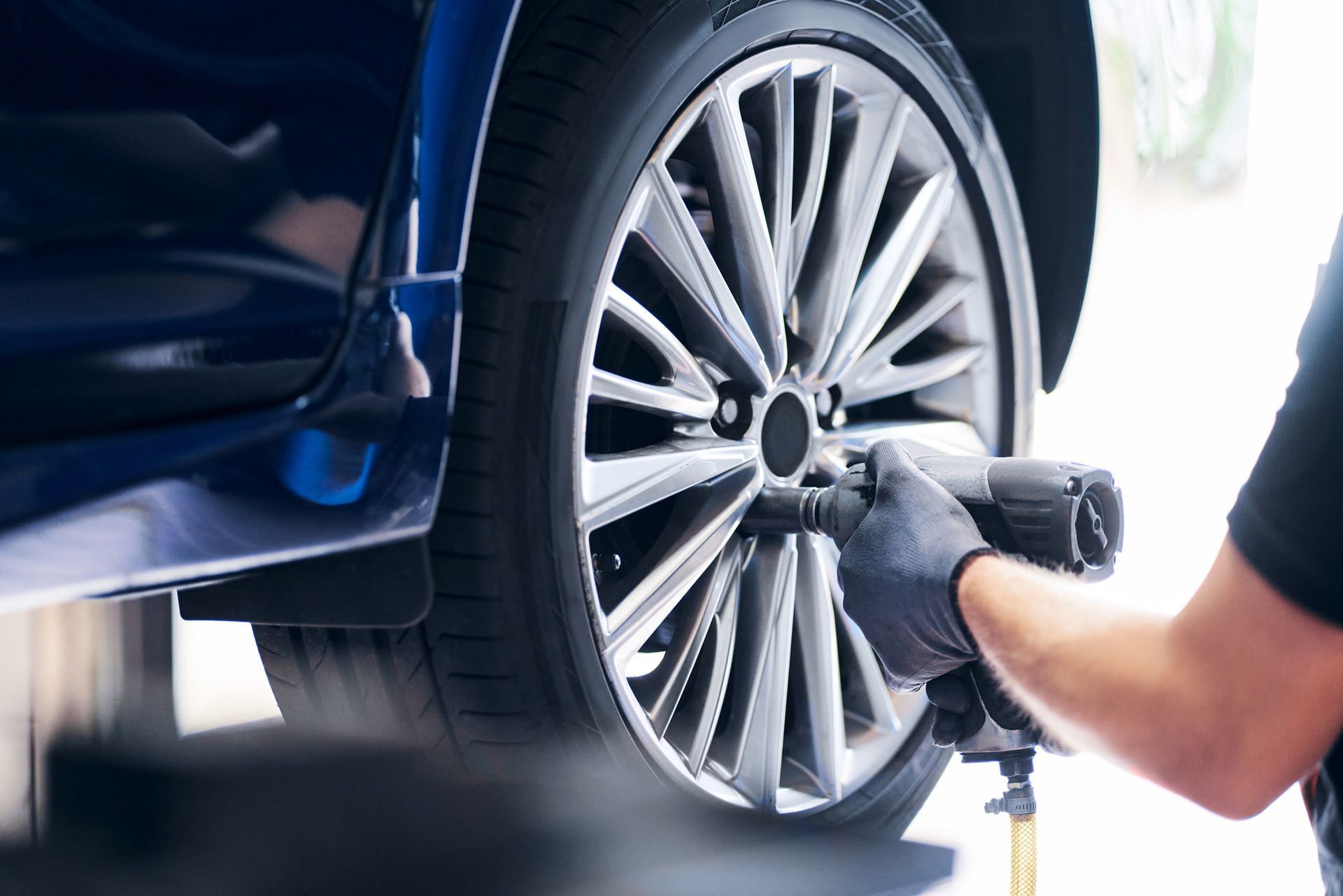 A person is working on a car engine with a wrench.