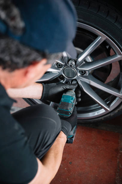 A man is changing a tire on a car with a wrench.