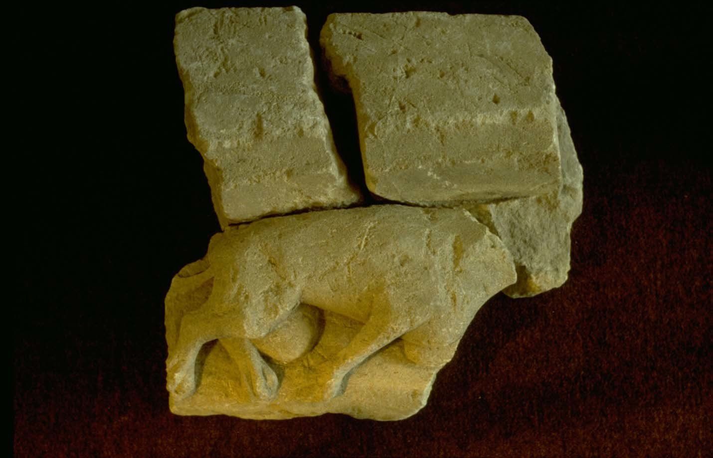 A piece of stone with a statue of a wolf on it.