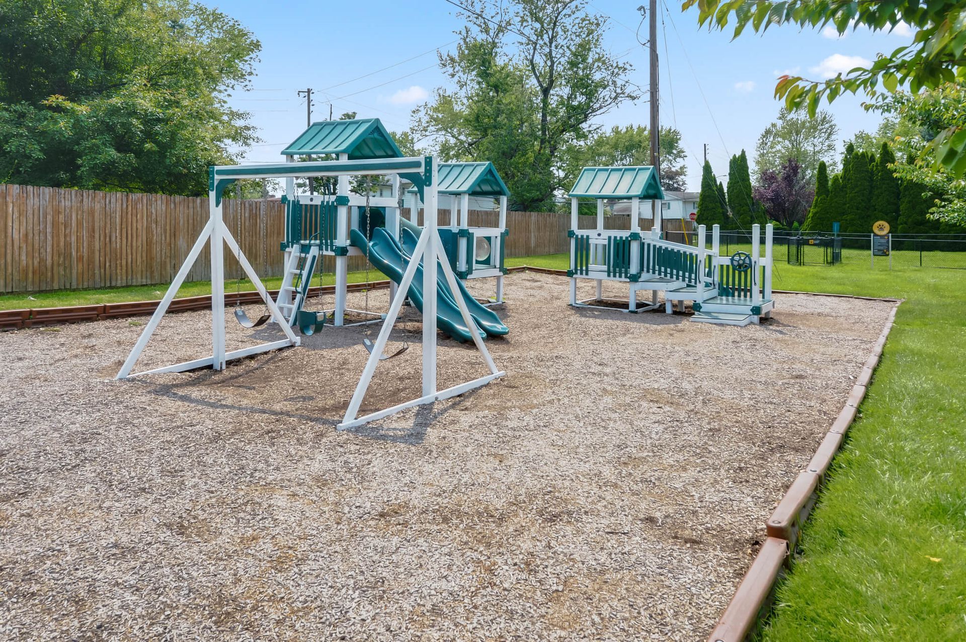 Outdoor playground with slides and swings on a gravel surface.