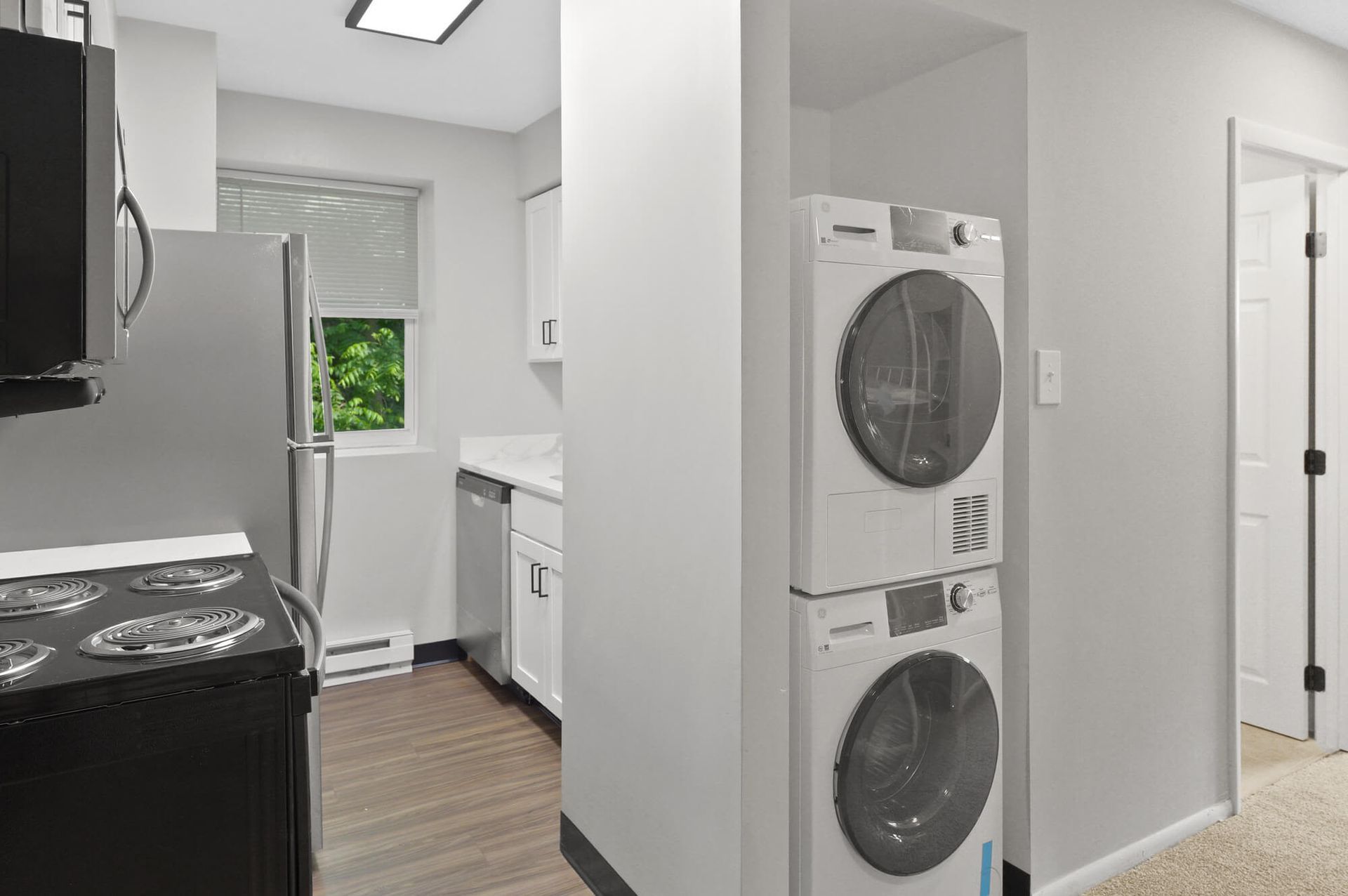 Compact apartment kitchen with stacked washer/dryer, refrigerator, stove, and dishwasher.