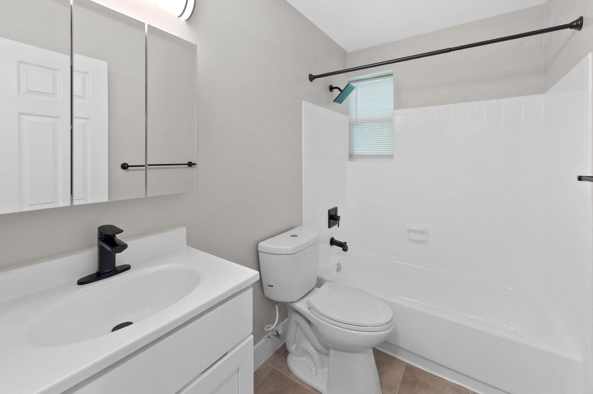 White bathroom with vanity, mirror cabinet, toilet, and tub/shower.