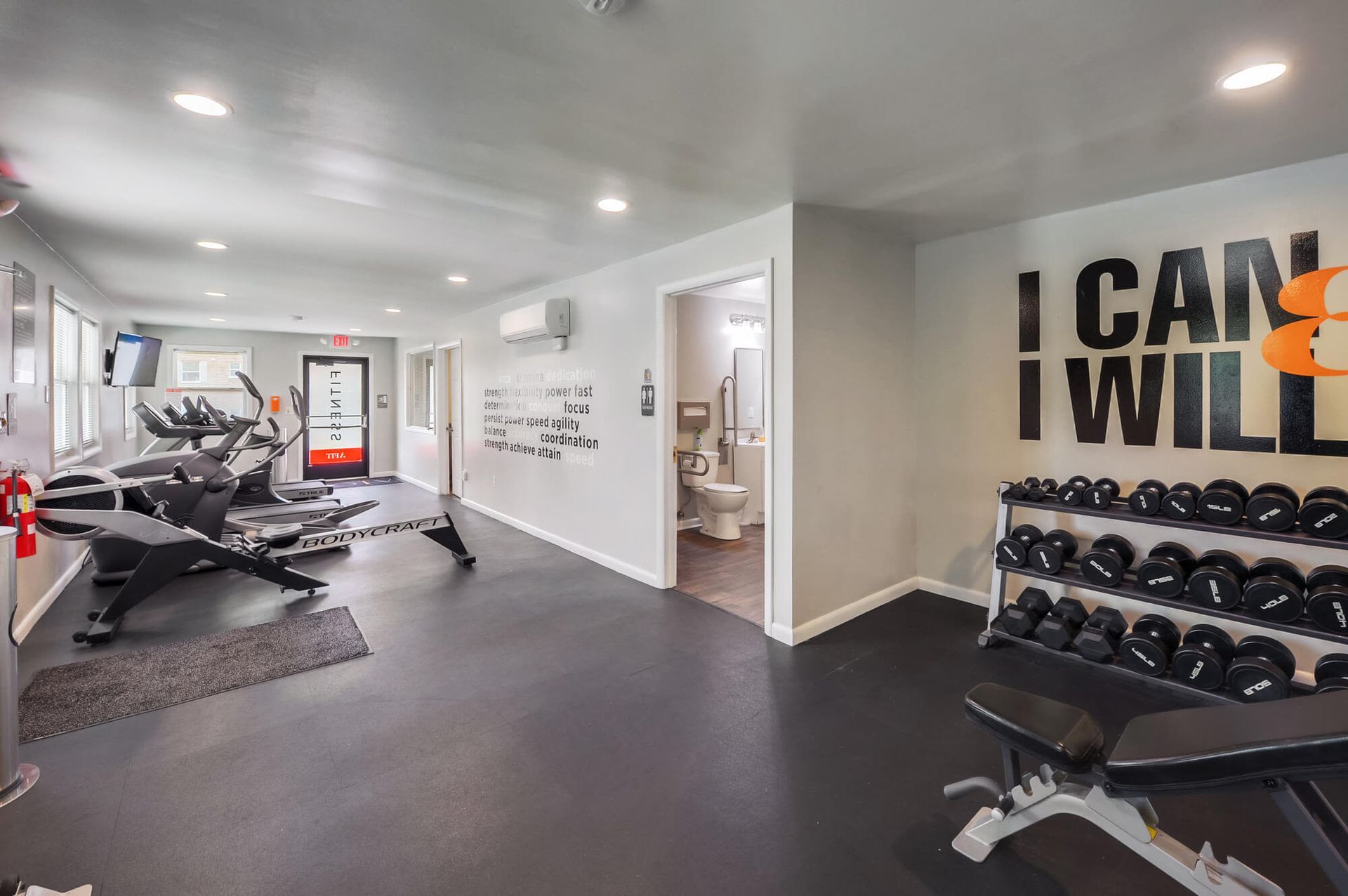 Indoor community gym with treadmills, weights, and a bench along a wall.