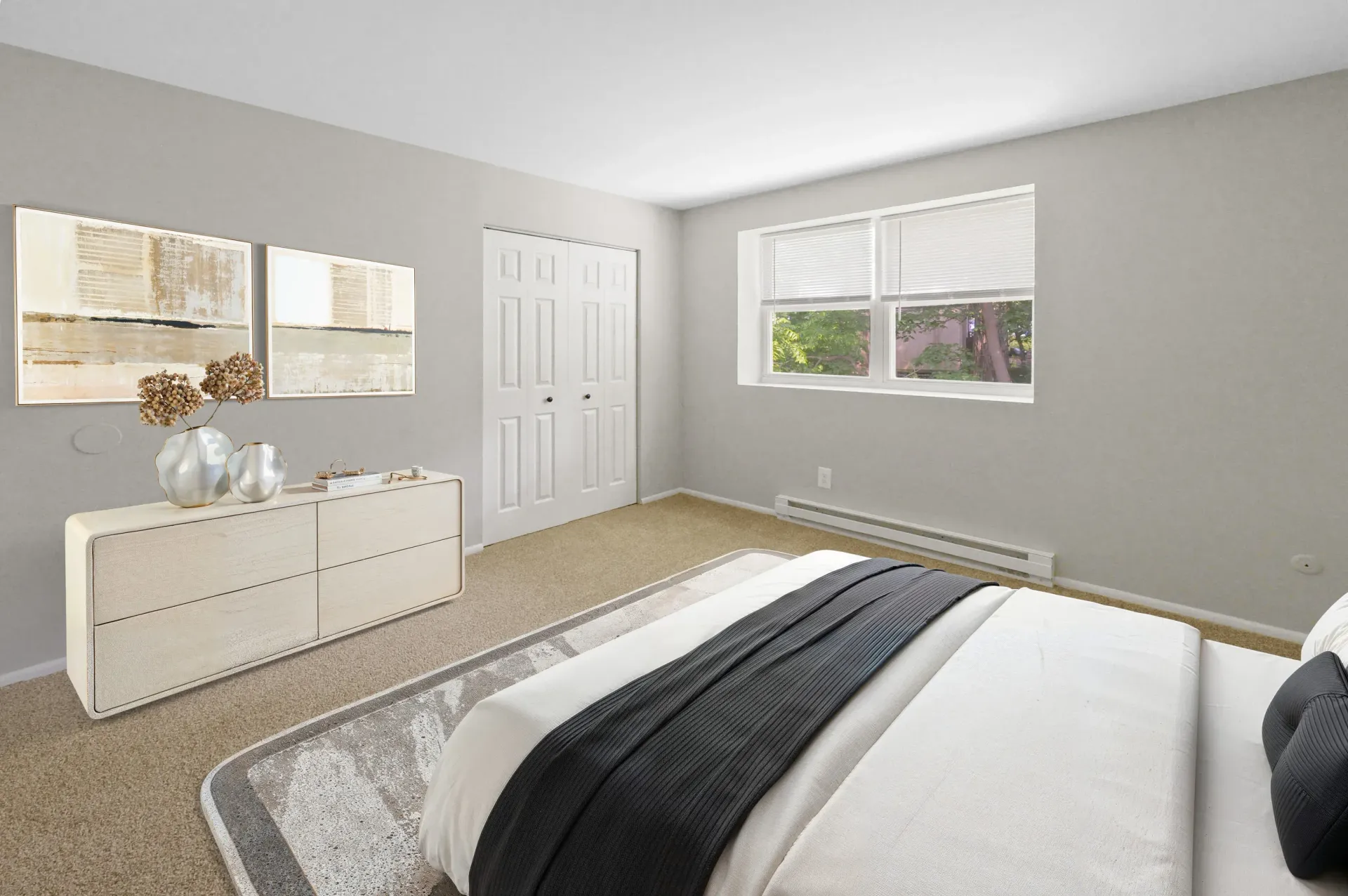 Bedroom in a neutral-toned apartment with a dresser, bed, and window.