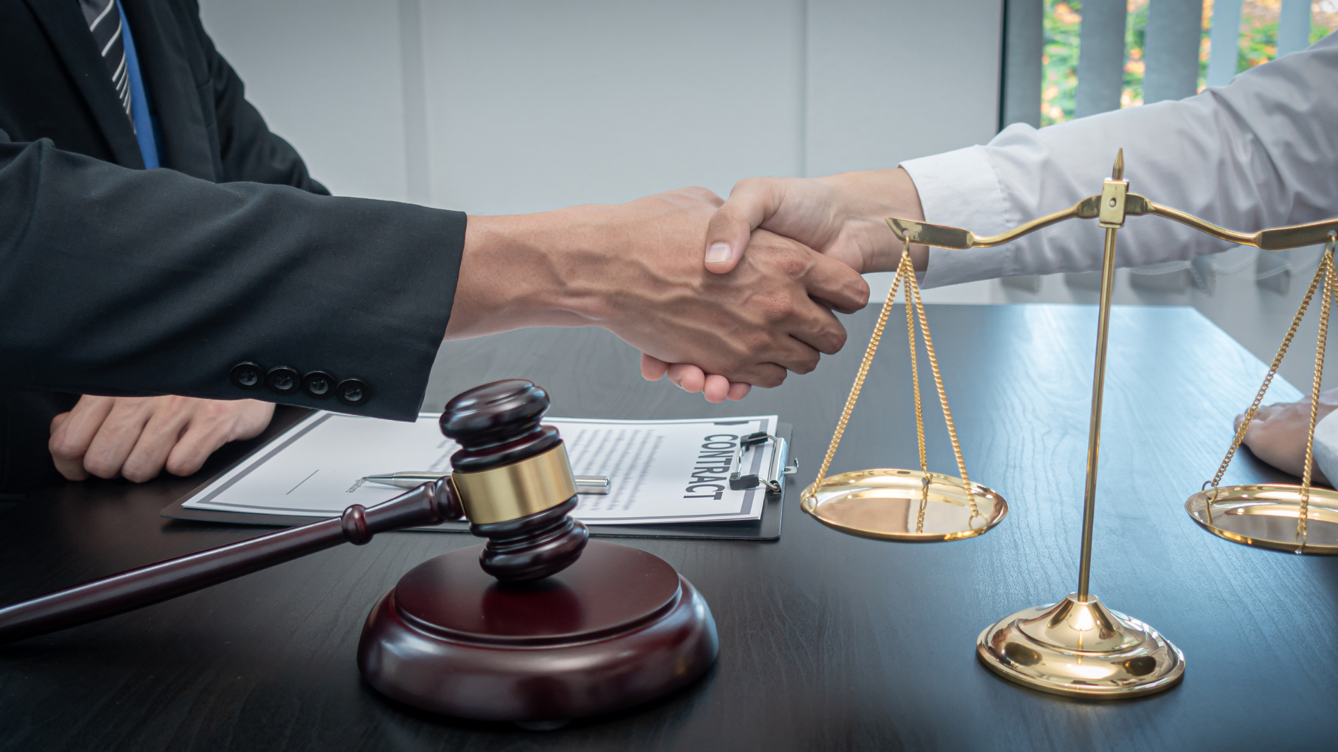 a judge is shaking hands with a client in front of a scale of justice .