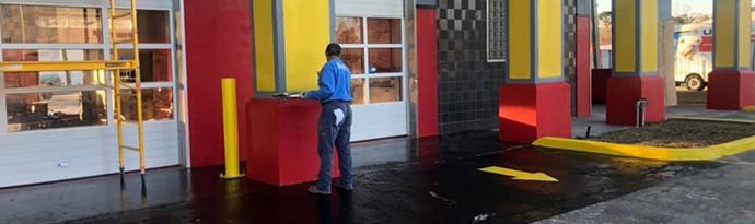 A man in a blue shirt is standing in front of a building. | Brakes For Less