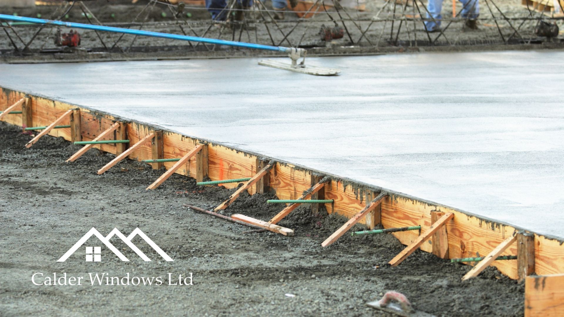 Wooden forms and stakes along a concrete curb during road construction beside a frozen water surface