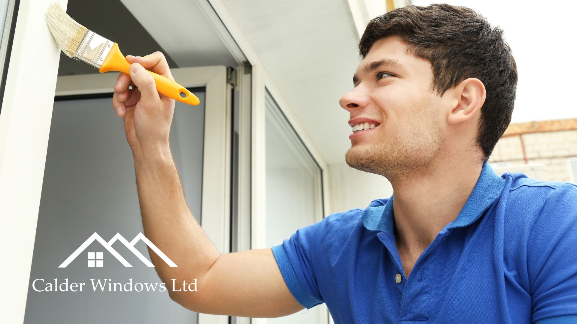 Person painting a window frame with a yellow brush, smiling in a bright indoor setting