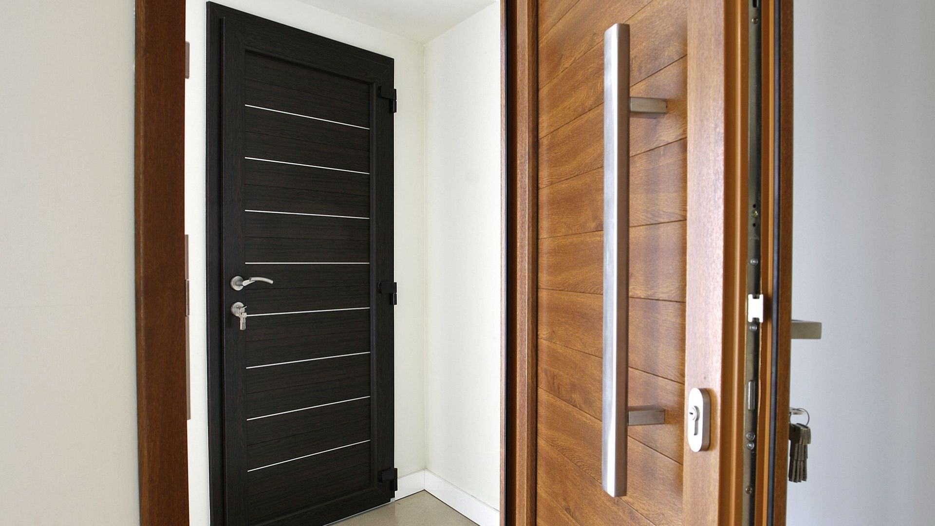 Interior hallway with a partially open wooden door and a black slatted door behind it