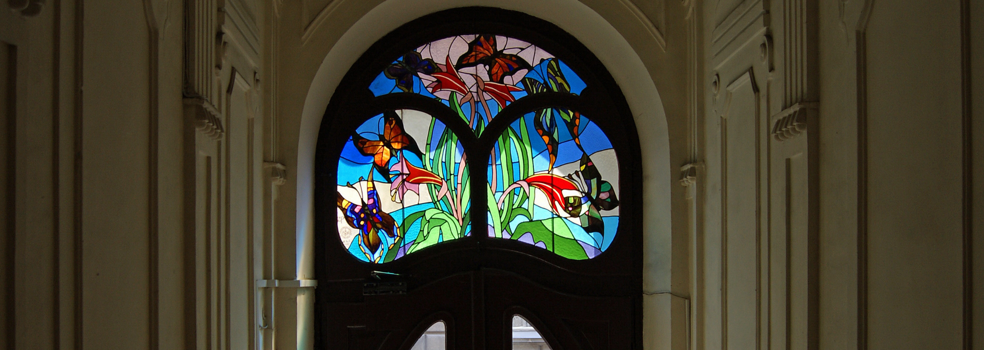 Colorful stained-glass window in a church interior, framed by stone arches.