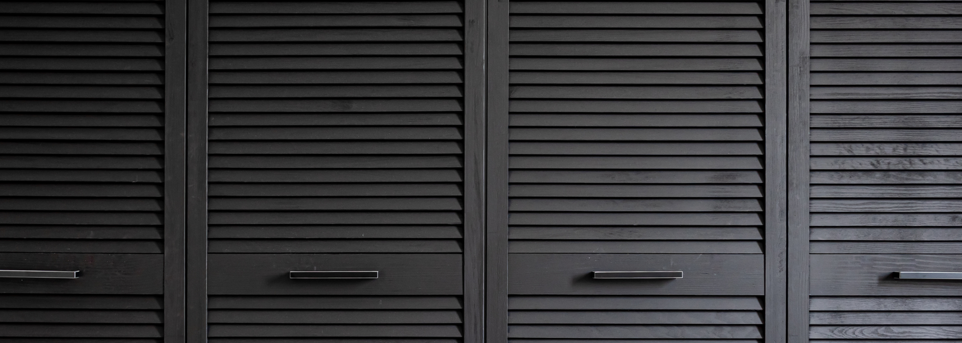Gray louvered closet doors with horizontal slats and small handles
