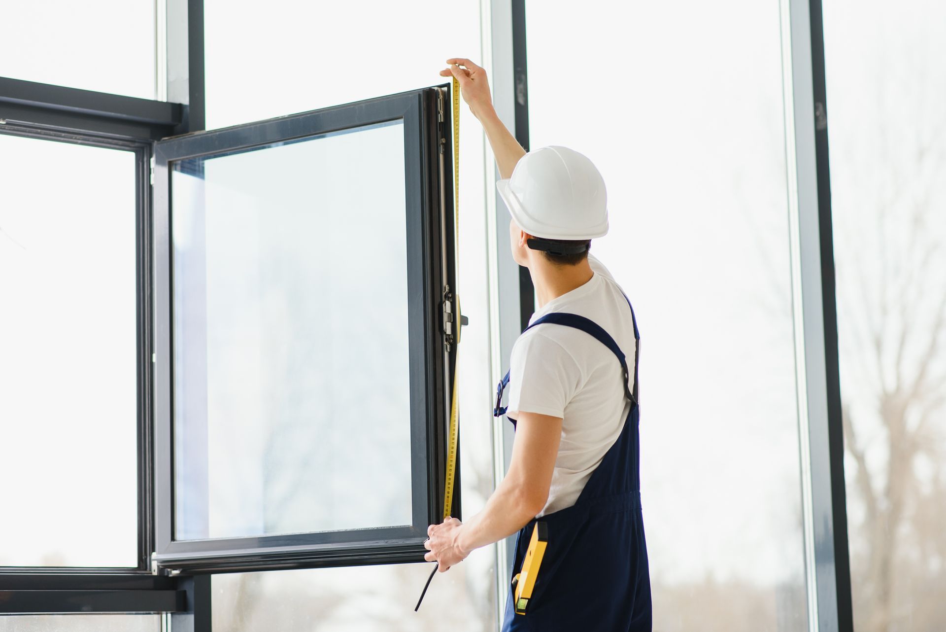 Worker in a hard hat opening a window indoors
