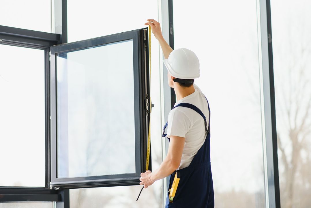 Worker in a hard hat opening a window indoors