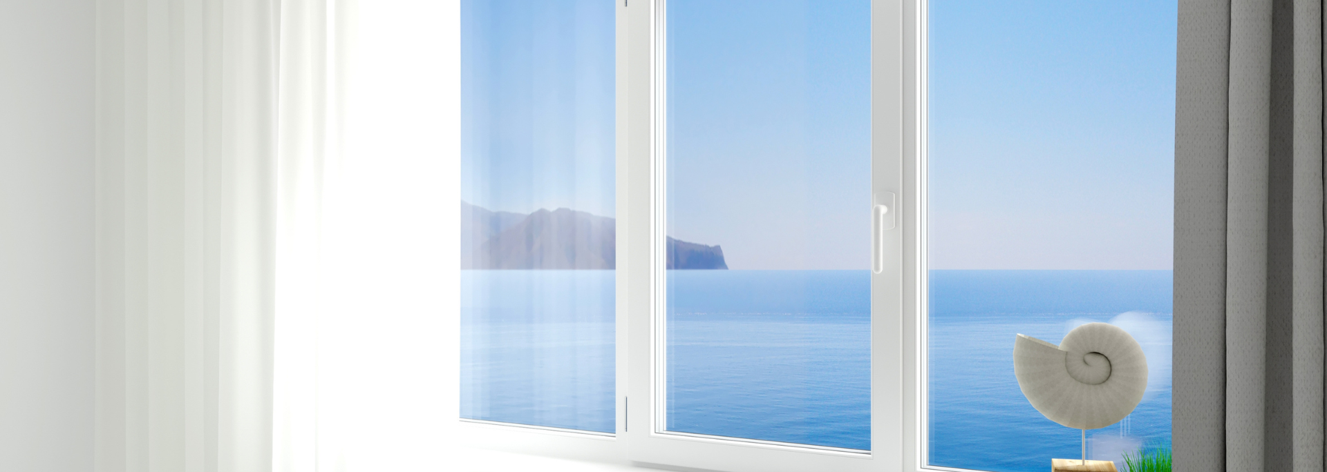 Sheer curtains framing a bright seaside view through white French doors, with a white shell sculpture on the sill