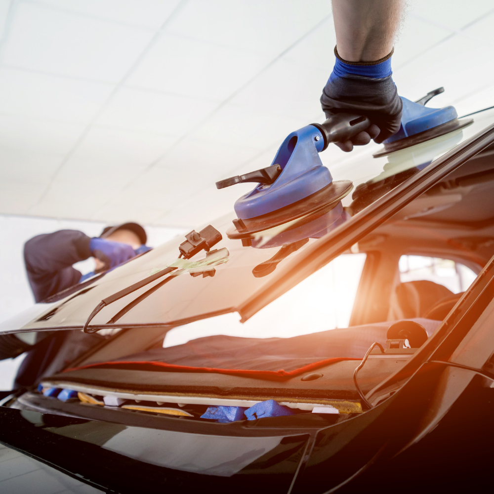 A man is installing a windshield on a car.