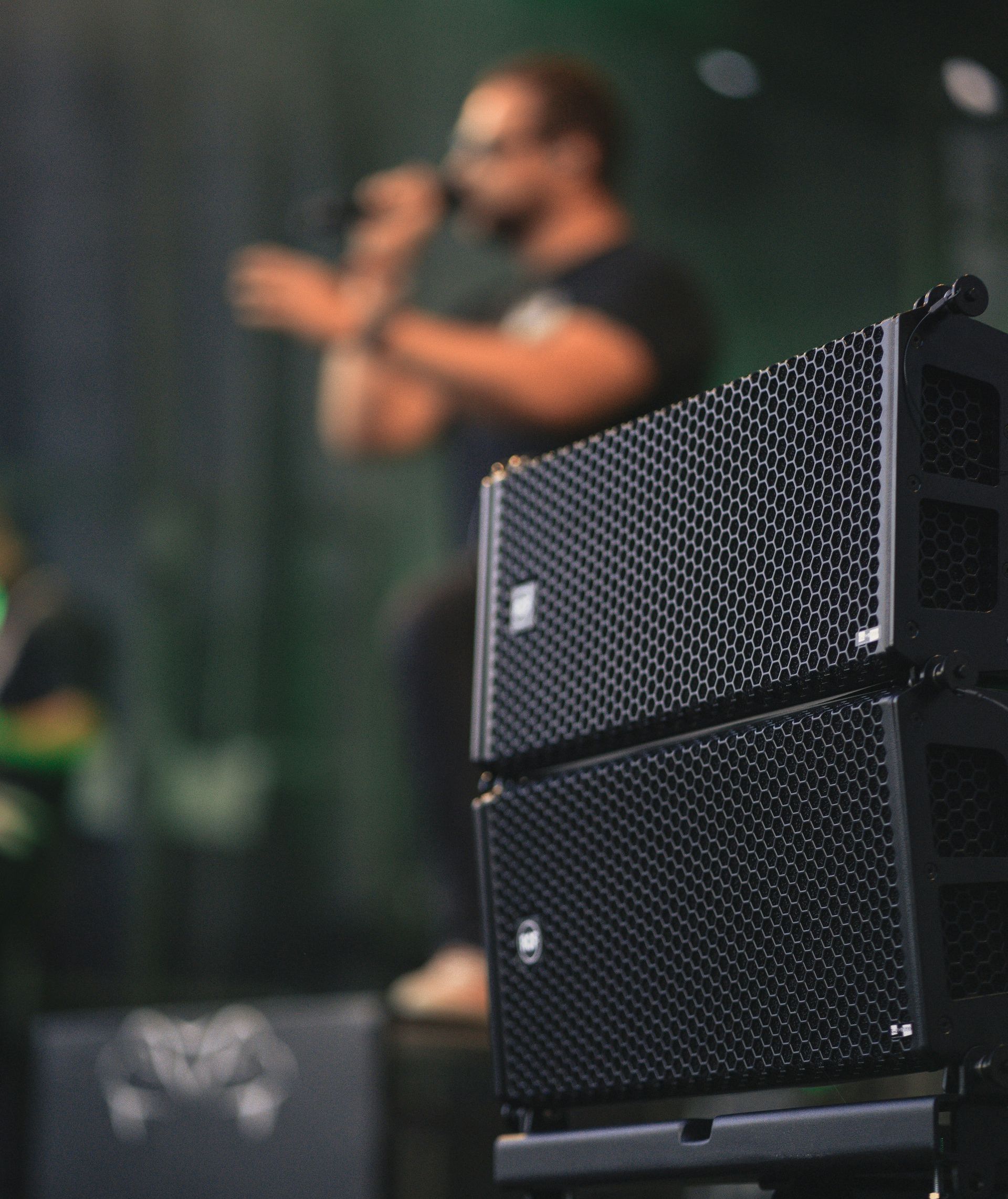 a man singing into a microphone behind a stack of speakers