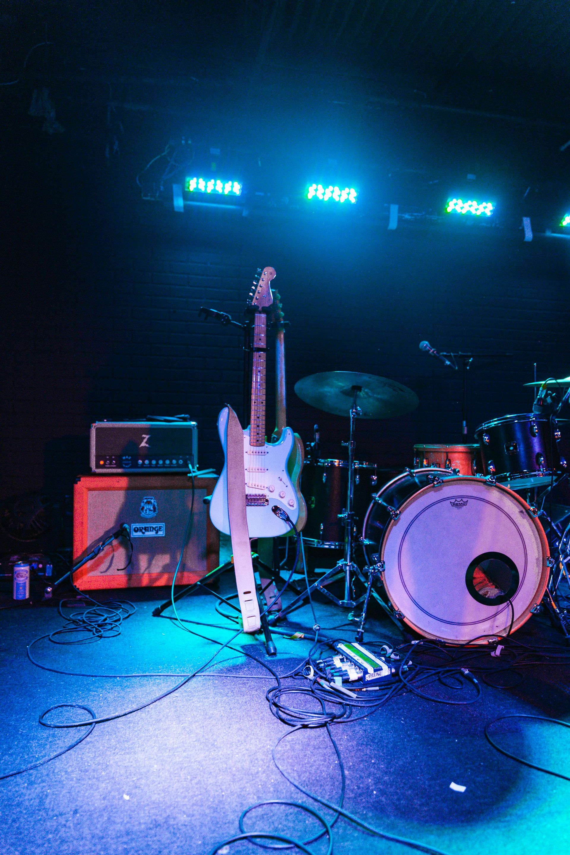 a guitar is sitting on a stage next to a drum set.