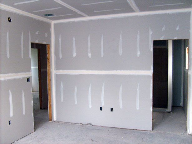 Interior room with drywall installation; walls and ceiling are grey with white joint compound.