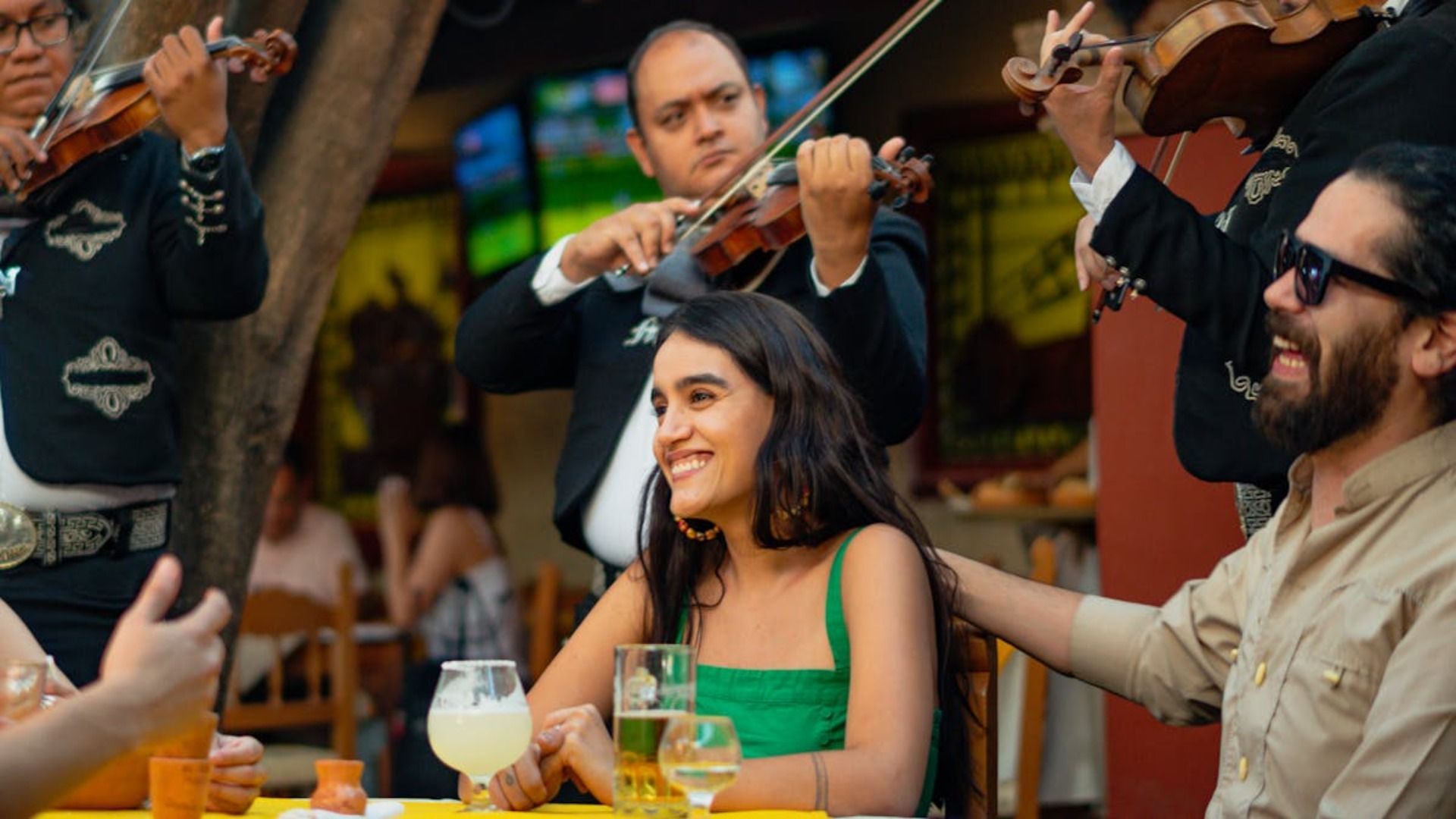 Un grupo de personas está sentada en una mesa frente a una banda de mariachis.