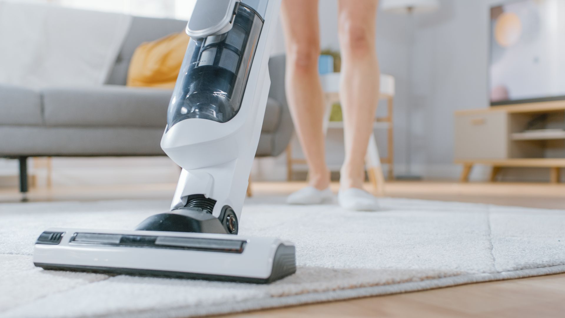 A Woman Is Using a Vacuum Cleaner to Clean a Rug in A Living Room