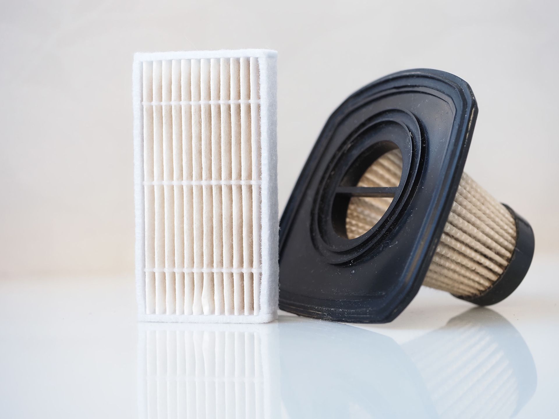 Two Vacuum Cleaner Filters Are Sitting on A White Surface