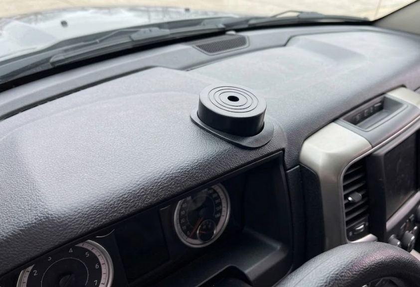 Pequeño dispositivo circular de color negro montado en el salpicadero del coche, encima del cuadro de instrumentos.