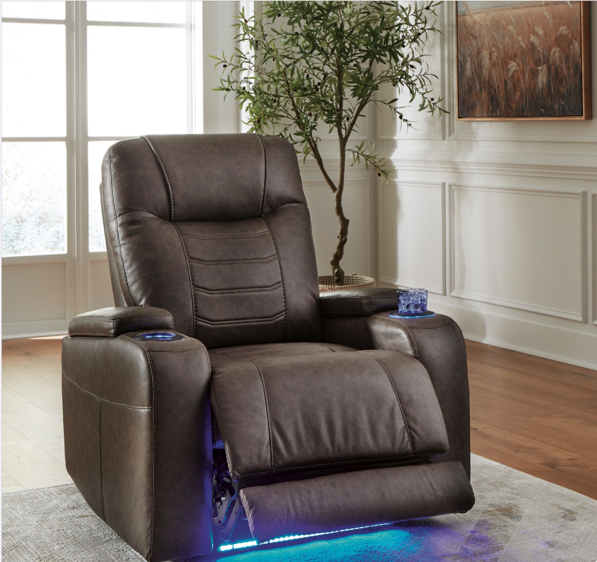 Brown leather recliner with blue under-lighting and cupholders, in a living room setting.
