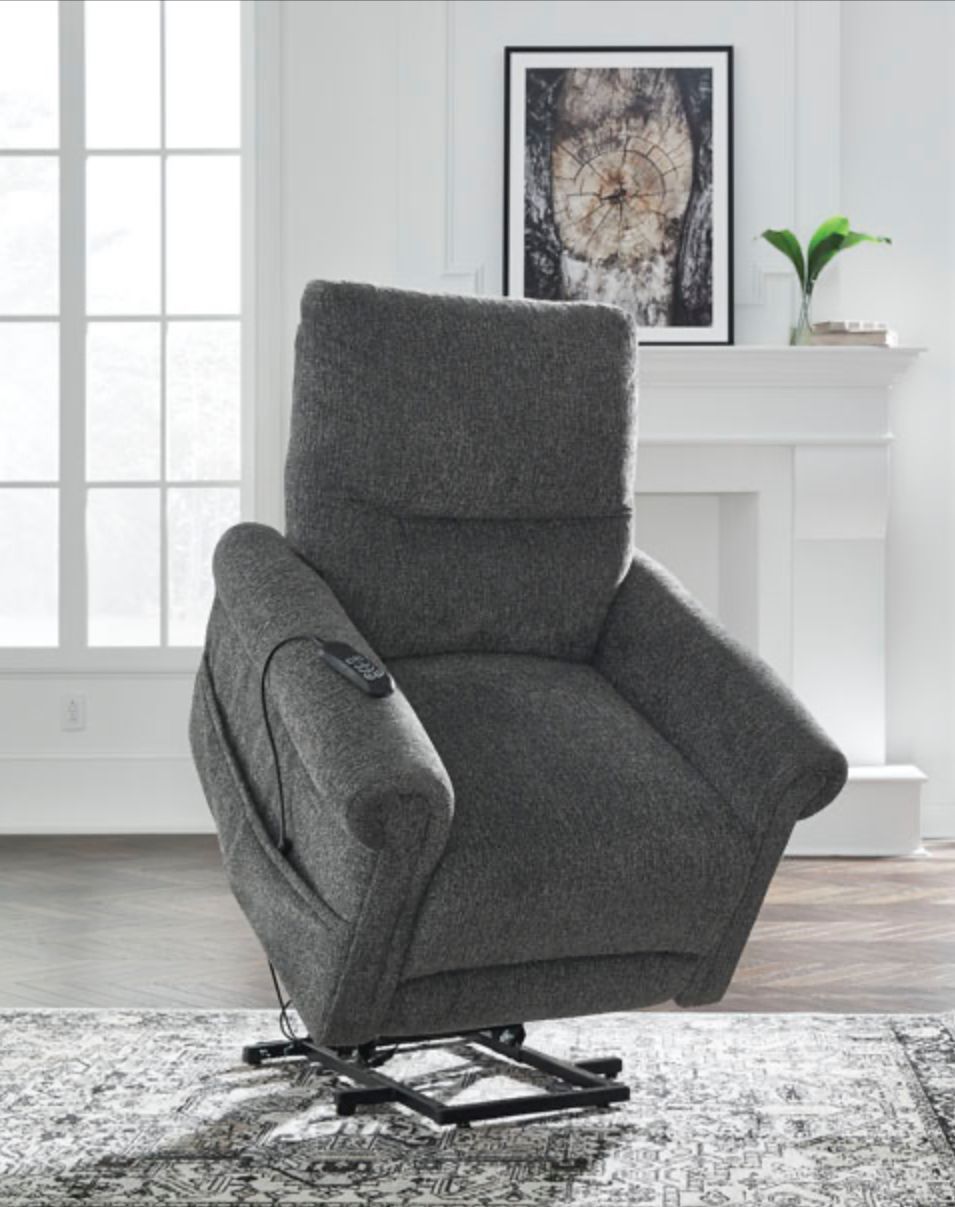 Gray lift chair in front of a window and fireplace.