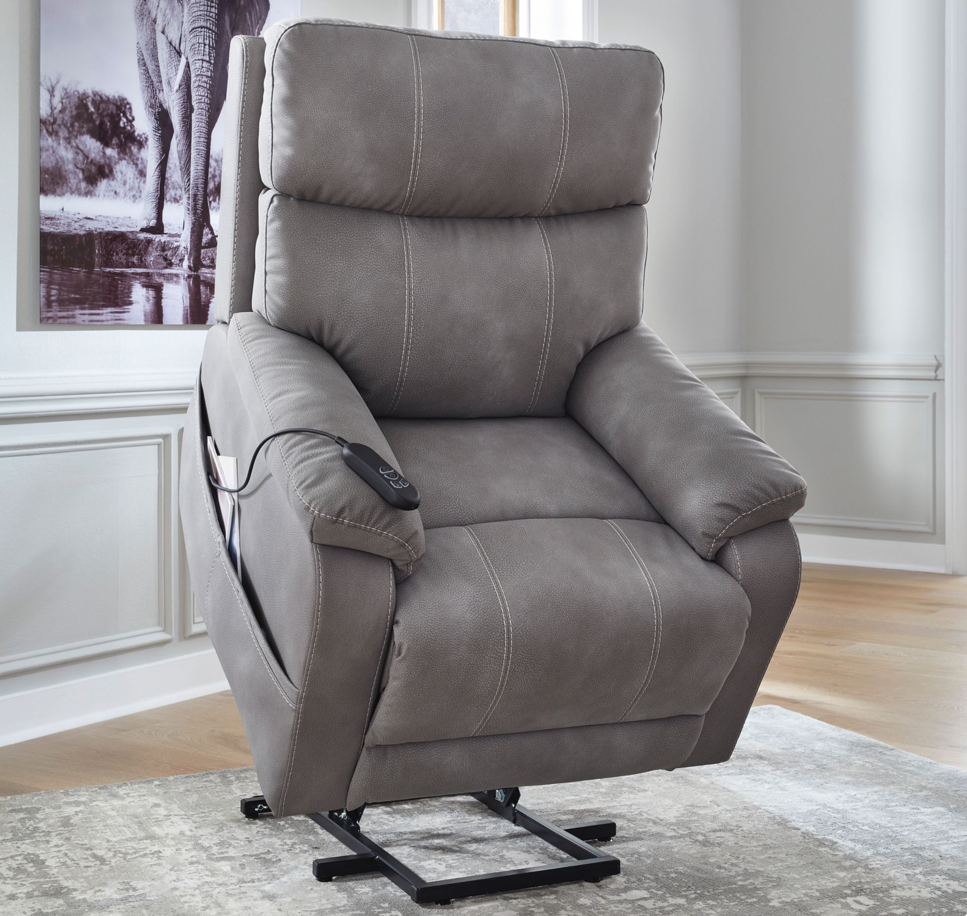 Gray power lift recliner with remote control, on a patterned rug.