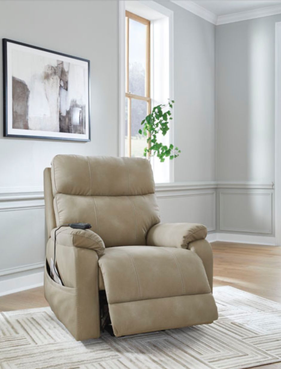 Beige power lift recliner chair in a light-colored room with art and a window.