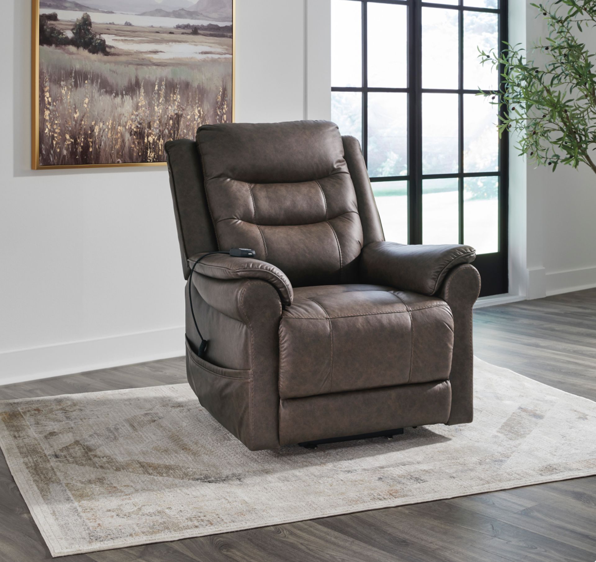 Brown leather power lift recliner chair on a rug, next to a window and art.