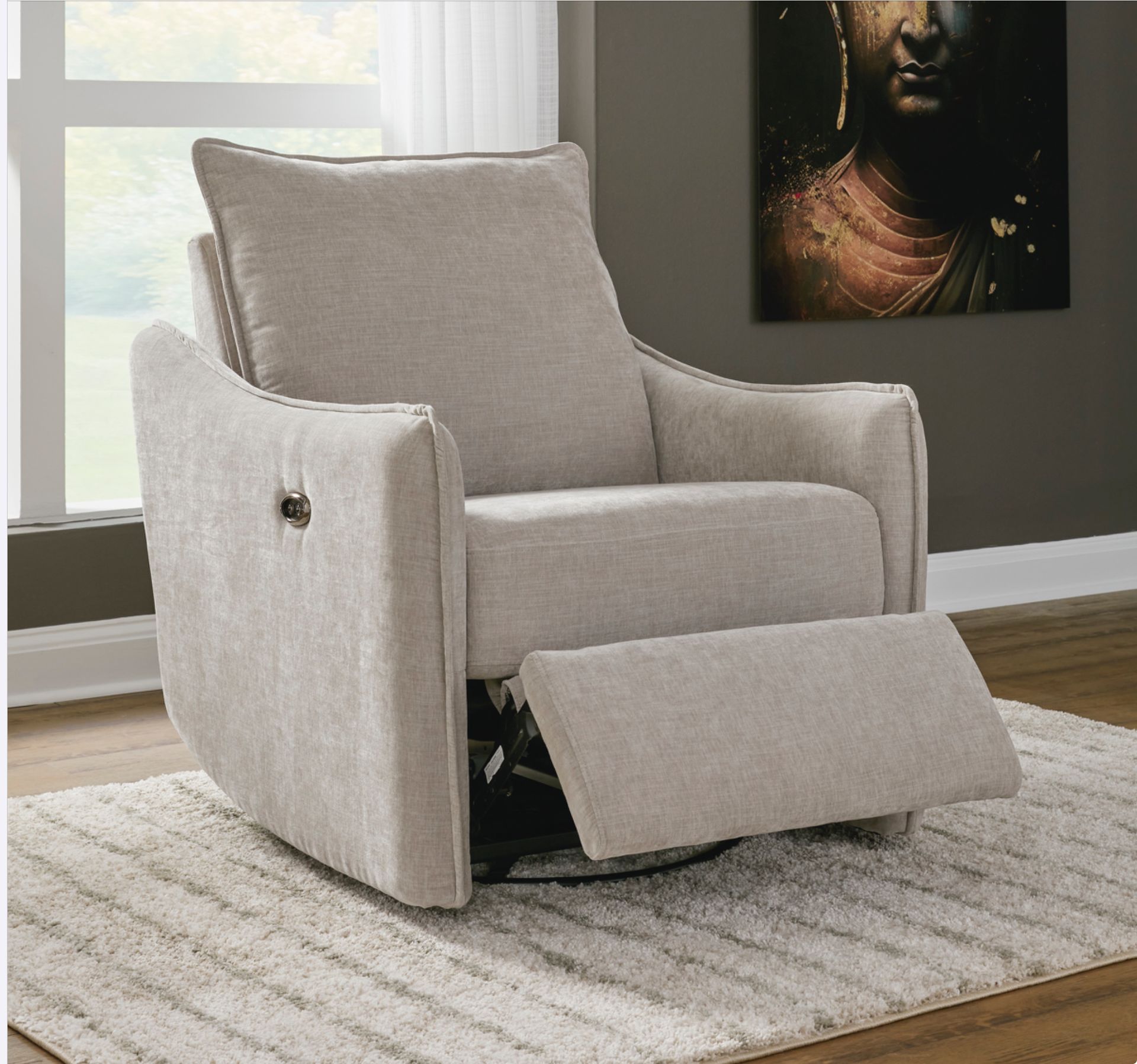 Beige recliner with extended footrest on a rug, near a window and artwork.