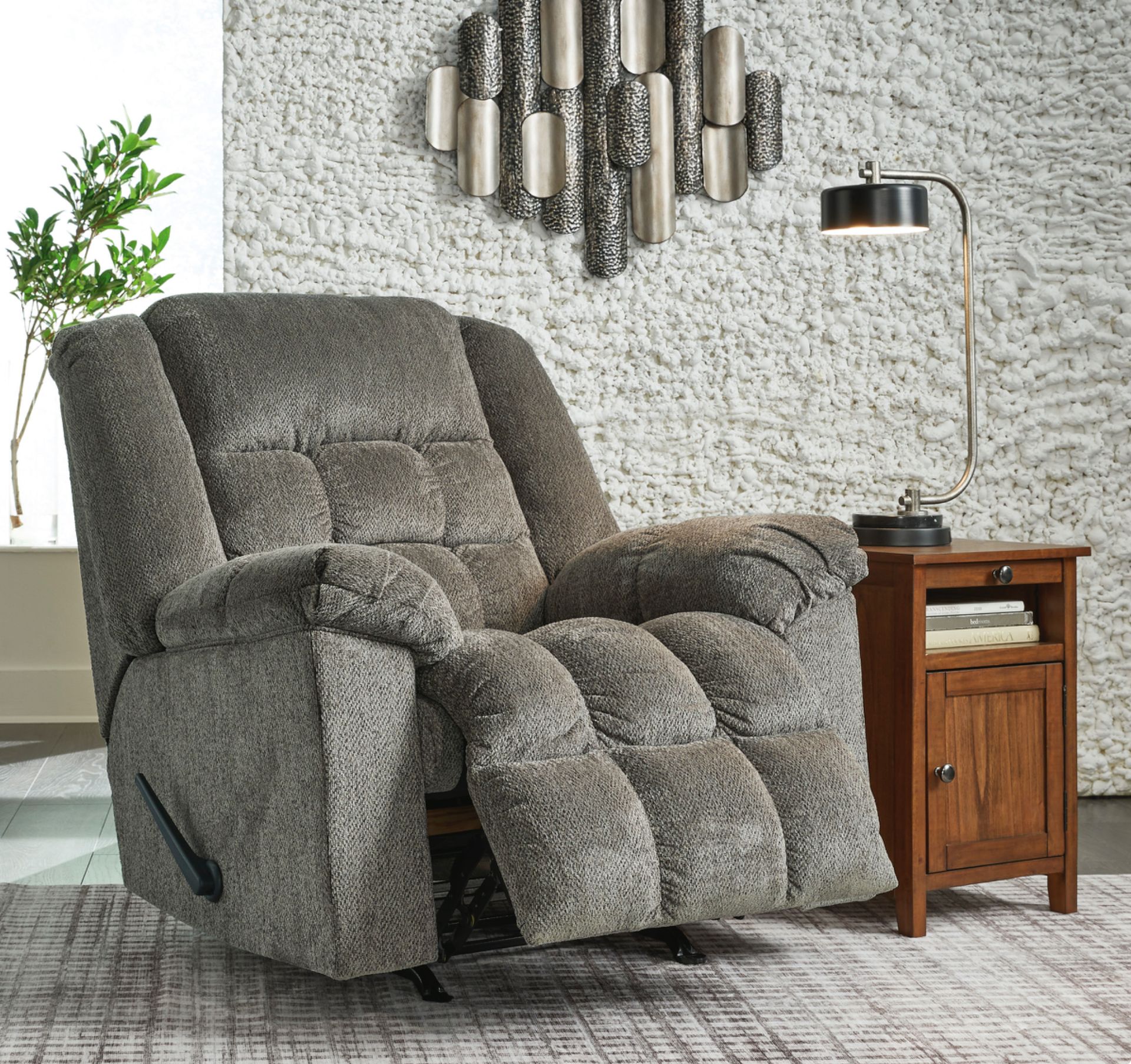 Gray patterned recliner chair in living room setting with side table and lamp.