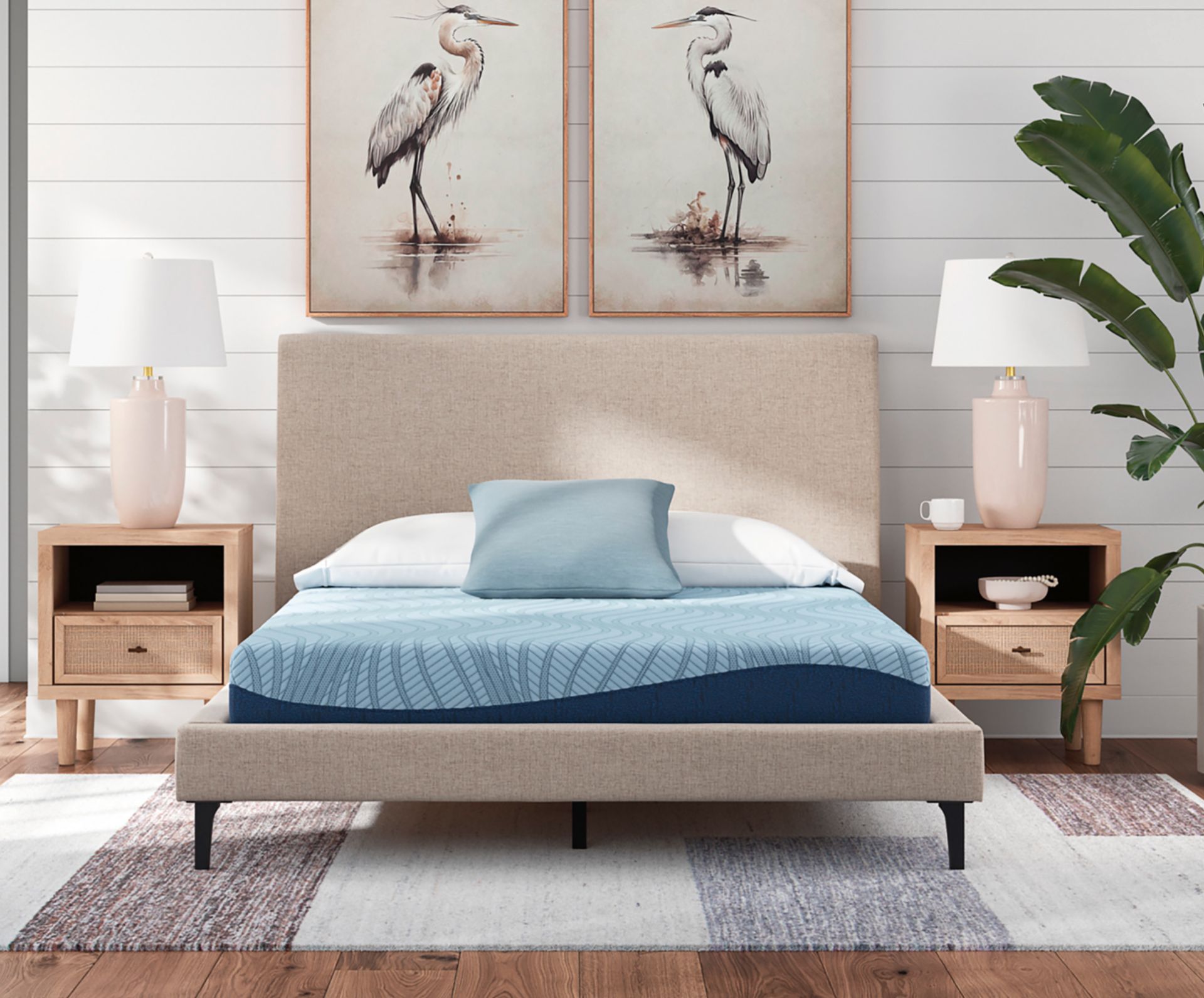 Bed with beige headboard and nightstands, framed art, and blue bedding.