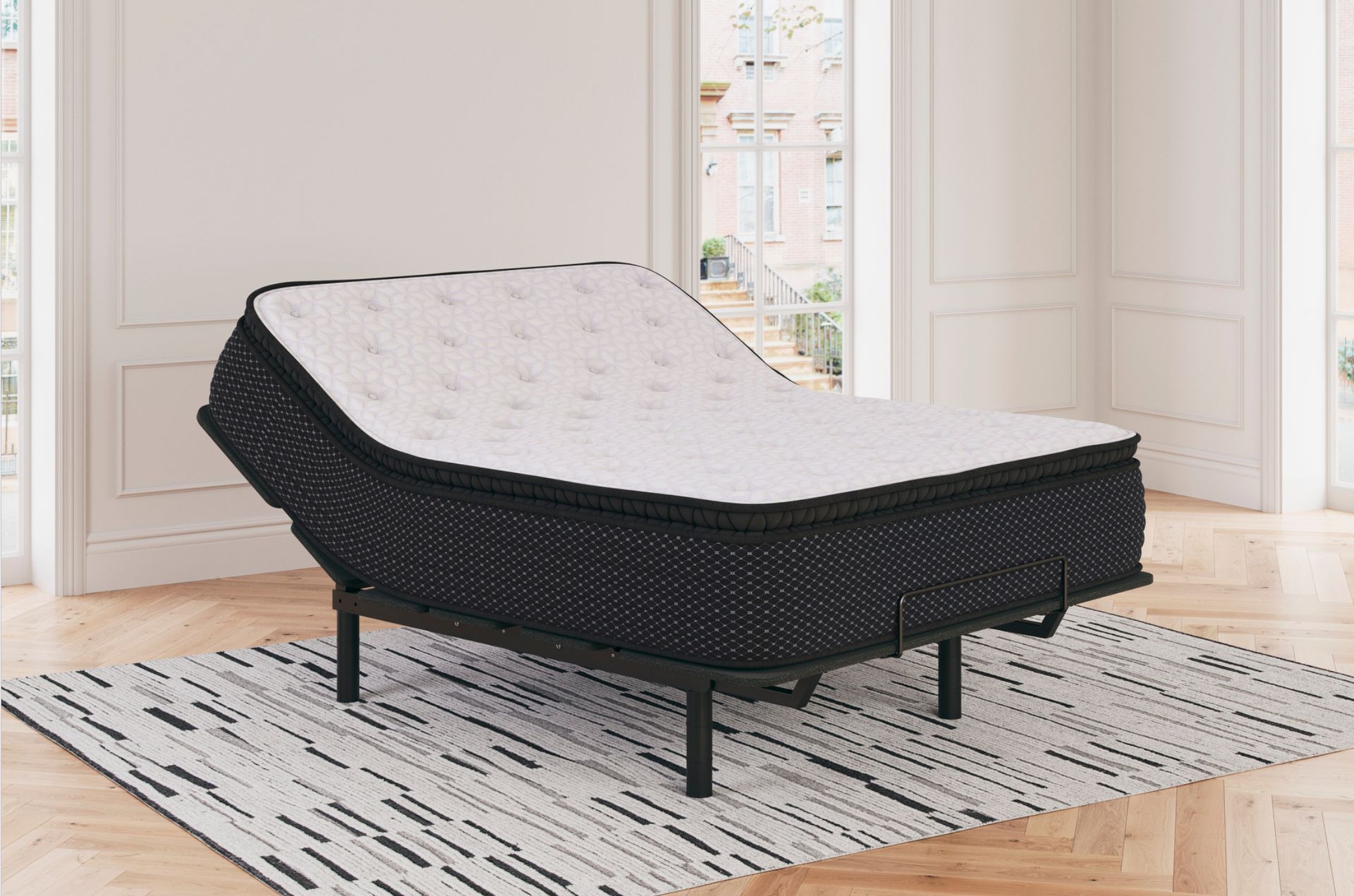 Adjustable bed with black base and white mattress in a room.