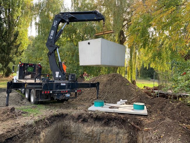 A narrow trench with black drainage pipes installed, a green PVC pipe visible.