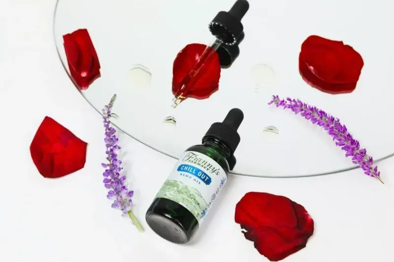 Bottle of Franny's Farmacy chill out CBD oil with dropper, surrounded by rose petals and lavender