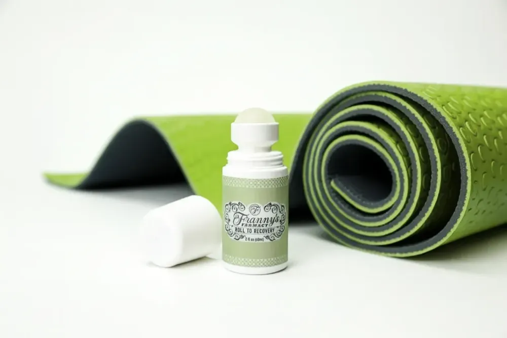 Green yoga mat with a CBD oil roller bottle; white backdrop.