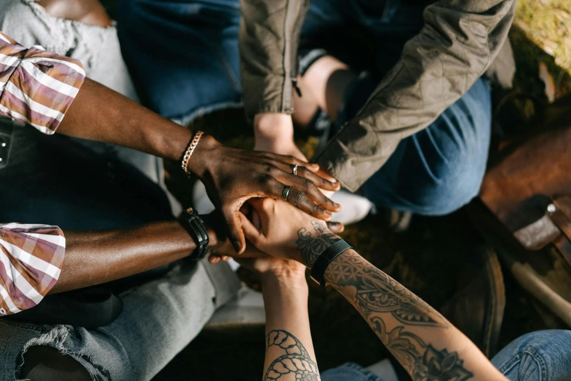 Hands of diverse people stacked together in a circle, symbolizing teamwork.
