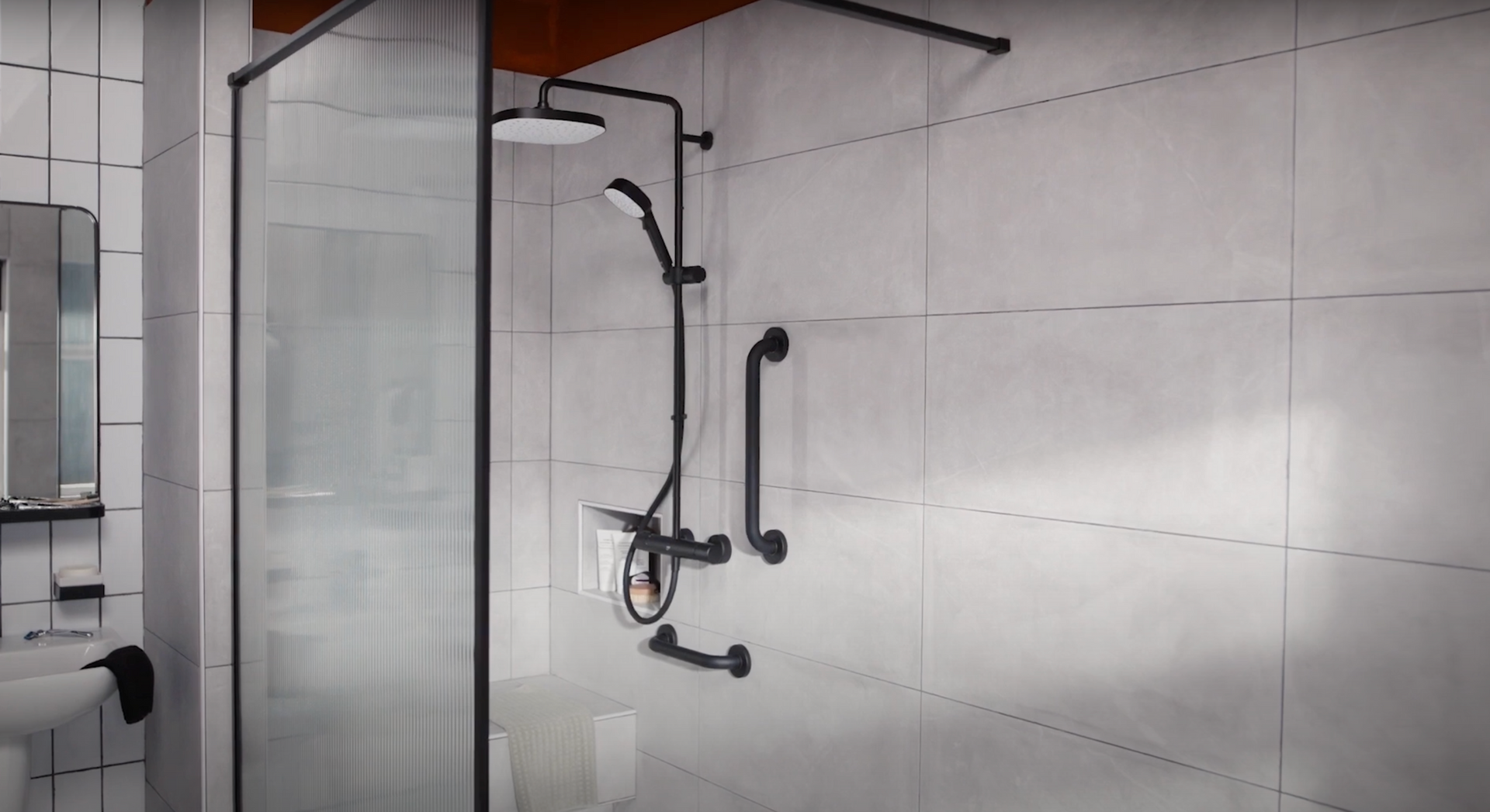A white tiled open concept shower with black accessibility handles