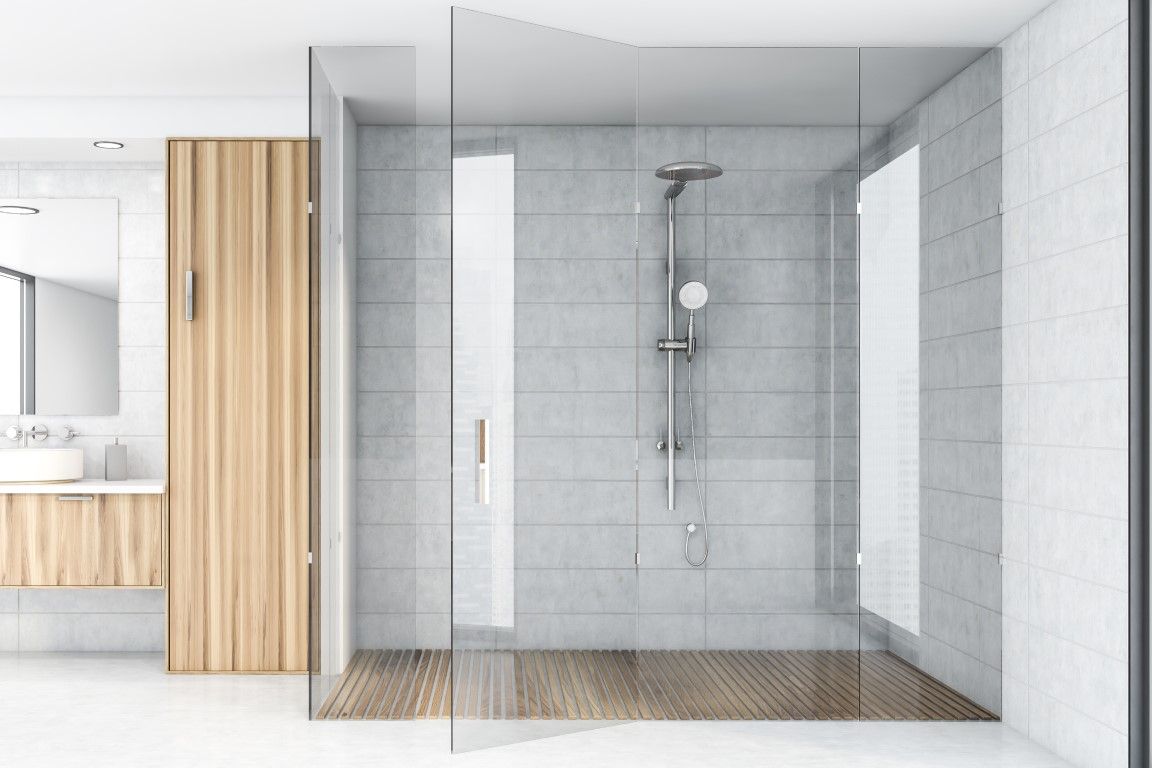 A large open glass shower with a rainfall showerhead, next to natural wood cabinets.
