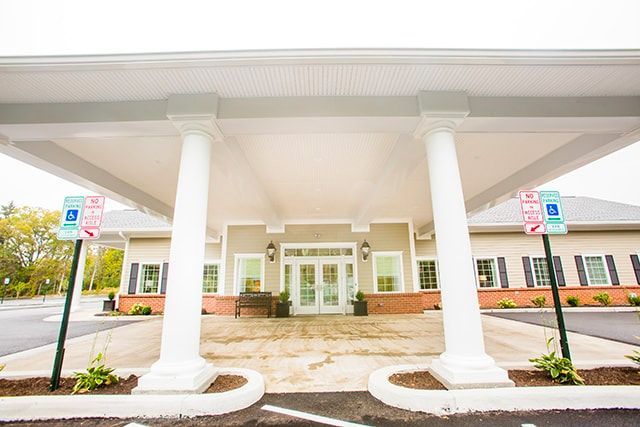 a large building with a covered entrance and a parking lot in front of it .